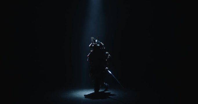 Asian man in traditional samurai costume stepping into the light with his sword prepared in hands, isolated on black background - culture, tradition concept 4k footage