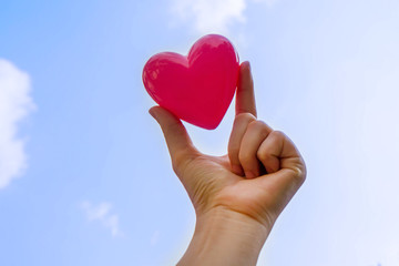 Hand holding heart with blue sky