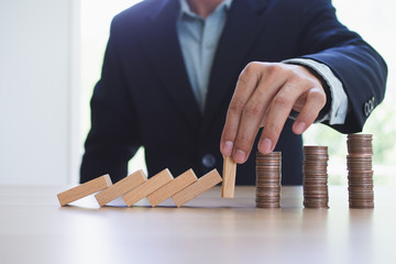 Protection finance from domino effect concept. Hands stop domino effect before destroy stack of money.