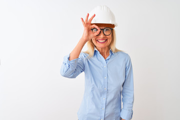 Middle age architect woman wearing glasses and helmet over isolated white background doing ok gesture with hand smiling, eye looking through fingers with happy face.