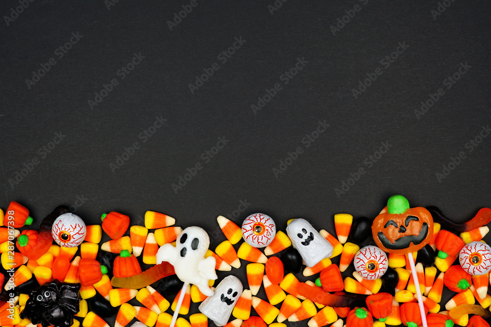 Poster Halloween candy bottom border. Top view on a black background with copy space.