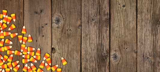 Halloween candy corn corner border banner. Top view on a rustic wood background with copy space.