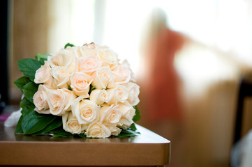 the bouquet lies on the edge of the table, and in the background the bride behind the curtain looks out the window
