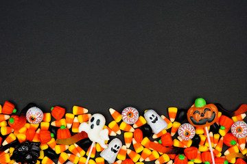Halloween candy bottom border. Top view on a black background with copy space.