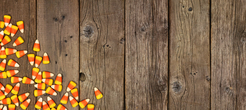Halloween candy corn corner border banner. Top view on a rustic wood background with copy space.