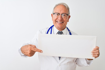 Senior grey-haired doctor man holding banner standing over isolated white background very happy pointing with hand and finger