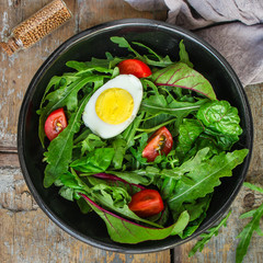 salad with boiled egg, tomtoo, mix lettuce leaves, appetizer, snack. food background. top view