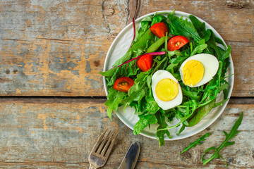 salad with boiled egg, tomtoo, mix lettuce leaves, appetizer, snack. food background. top view