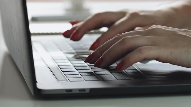 Woman hands with red manicure using laptop to work study and writing on paper with a pen. Business, financial, trade stock maket and social network concept.