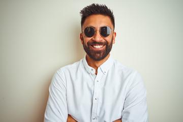 Obraz premium Handsome indian buinessman wearing shirt and sunglasses over isolated white background happy face smiling with crossed arms looking at the camera. Positive person.