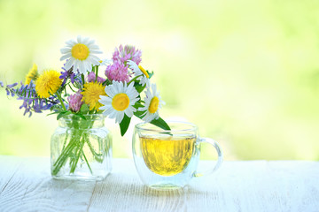 beautiful scene with bouquet wild meadow flowers and tea cup. Herbal organic tea, summer season. tea time. copy space. shallow depth, soft selective focus