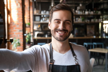 Smiling young waiter wear apron take selfie looking at camera