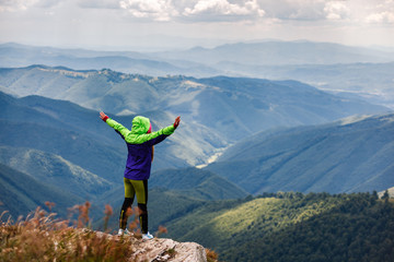 Young traveler standing on the peak of mountain feeling freedom. Dramatic picture.