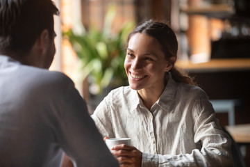 Smiling woman talking to boyfriend at romantic date in cafe
