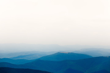 Mountain view with blue hills and white sky in the fog.