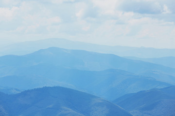 Beautiful landscape with blue silhouettes of hills and mountains with blue sky. Background