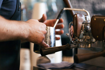 Barista steaming milk for hot cappuccino with machine