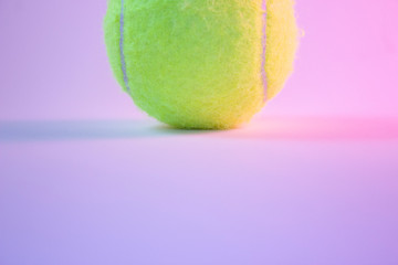 Yellow tennis ball on white background with pink and blue light. Part of ball