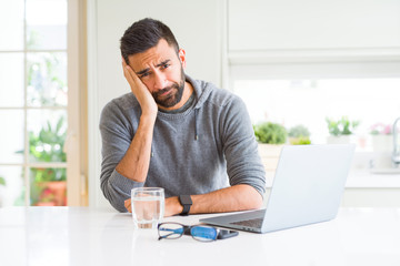 Handsome hispanic man working using computer laptop thinking looking tired and bored with depression problems with crossed arms.