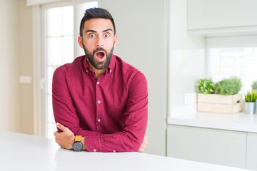Handsome hispanic business man afraid and shocked with surprise expression, fear and excited face.