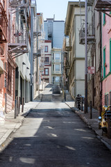 Narrow steep street in San Francisco with clean sidewalks and old fire escapes