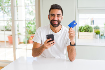 Handsome man using credit card to pay online with smartphone