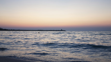 Fototapeta premium Sunset on the blue sea with breakwater into the dictance