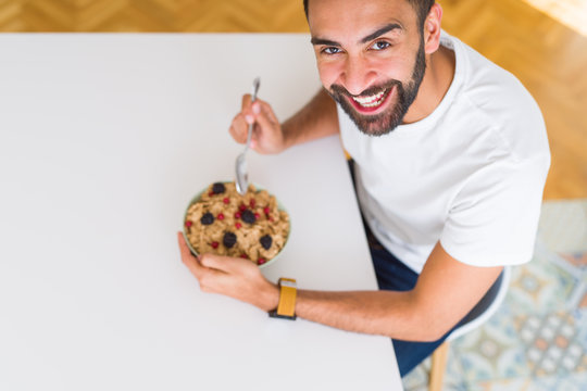 Above angle of handsome man eating healthy cereals for breakfast in the morning