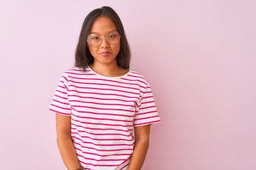 Young chinese woman wearing striped t-shirt and glasses over isolated pink background depressed and worry for distress, crying angry and afraid. Sad expression.