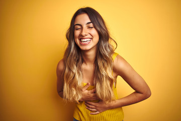 Young beautiful woman wearing t-shirt over yellow isolated background smiling and laughing hard out loud because funny crazy joke with hands on body.