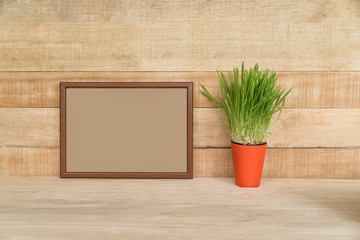 Empty frame on a wooden wall. Green houseplant on the table. Place for text.