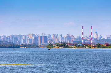 Summer sunny hot evening. Modern residential areas southern suburbs and midtown on hills in Kyiv on the right bank of the Dnipro River. Fishermen on boats on foreground. Kyiv. Ukraine. Aug. 28, 2019