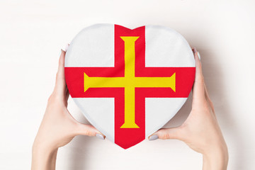 Flag of Guernsey on a heart shaped box in a female hands. White background