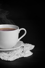 warming cup of hot black tea on the black background