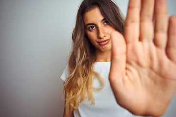 Fototapeta na wymiar Young beautiful woman wearing t-shirt over white isolated background with open hand doing stop sign with serious and confident expression, defense gesture