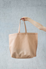 Large eco shopping bag in the hand of a young woman. Copy space. White background