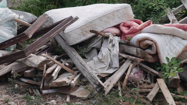 Garbage dumped in the yard near the house: boards, mattress, comforter