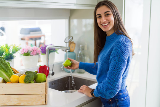 Young woman washing vegetables and fruit using water from sink