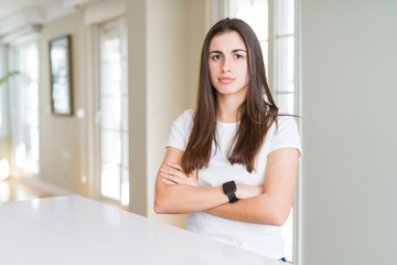 Beautiful young woman wearing casual white t-shirt skeptic and nervous, disapproving expression on face with crossed arms. Negative person.
