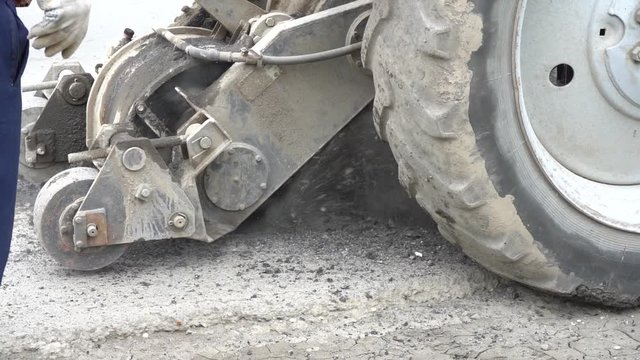 Road milling machine cuts the old asphalt. Road repair. Destruction of the road surface. The cutter cuts a layer of asphalt. Pieces of stone fly apart. Close-up