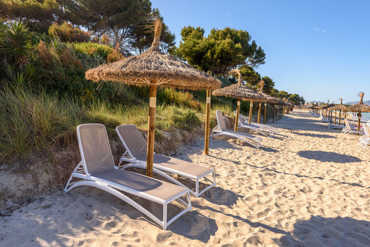 Sunbeds with umbrellas at the Playa de Muro beach in Mallorca, Spain