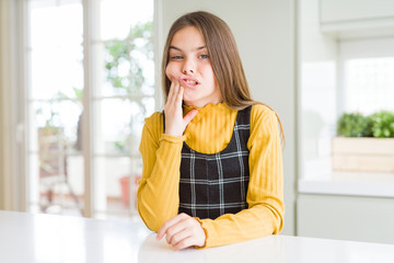 Young beautiful blonde kid girl wearing casual yellow sweater at home touching mouth with hand with painful expression because of toothache or dental illness on teeth. Dentist concept.