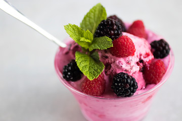 Homemade sorbet made from fresh berries with mint in glass bowl on a gray background.