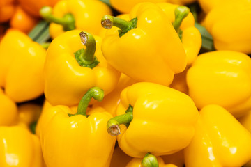 Bunch of yellow peppers in farmer's market or grocery store. Vegetable background. Spicy and sweet plant for sustainable diet.