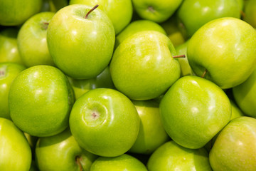 Shiny green apple close-up pile for background, healthy snack option, bite
