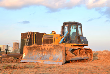 Obraz premium Track-type bulldozer, earth-moving equipment. Land clearing, grading, pool excavation, utility trenching, utility trenching and foundation digging during of large construction jobs.