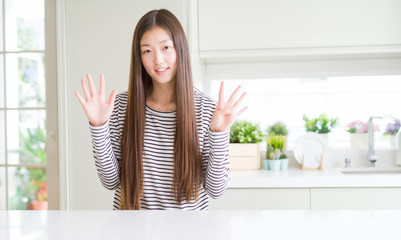 Beautiful Asian woman wearing stripes sweater showing and pointing up with fingers number nine while smiling confident and happy.