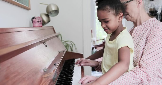 Grandmother teaching grandchild to play the piano