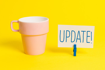 Word writing text UPDATE. Business photo showcasing make something more modern or up to date like software program Cup empty paper blue clothespin rectangle shaped reminder yellow office