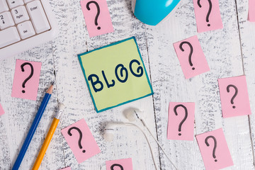 Text sign showing Blogquestion. Business photo showcasing regularly updated website web page run by individual Writing tools, computer stuff and scribbled paper on top of wooden table